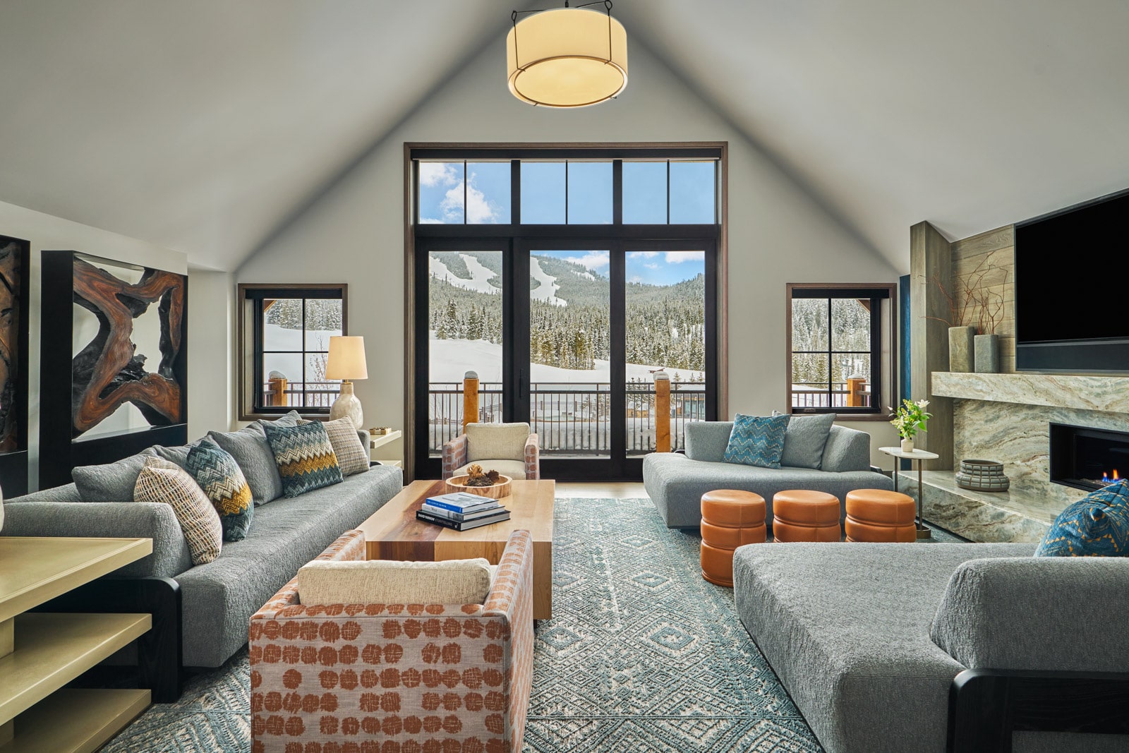 A living area with several sofas looks out onto a snowy mountain slope.