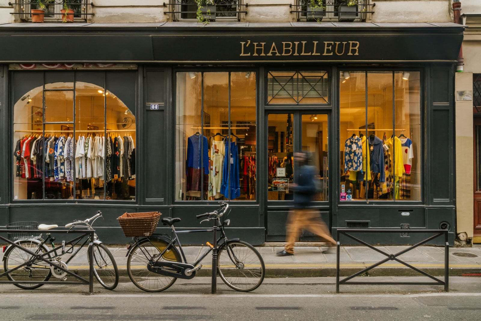 Two bicycles parked in front of a clothing store in Paris, France.