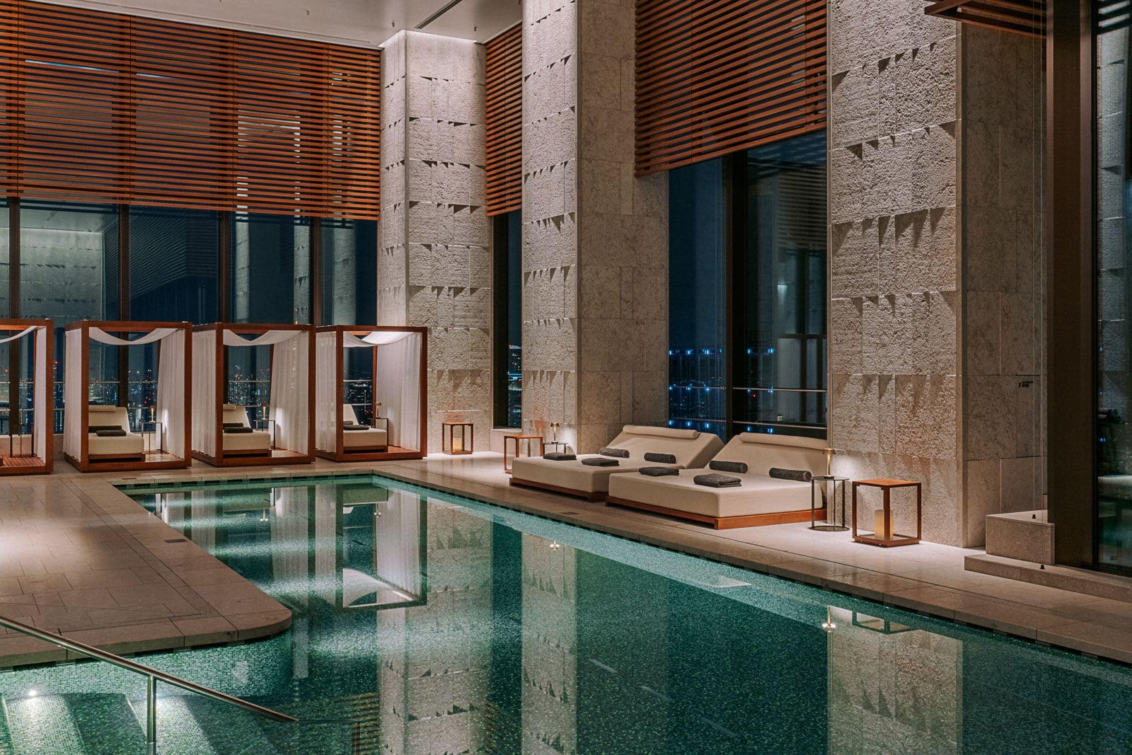 An indoor pool with lounge chairs and cabanas.